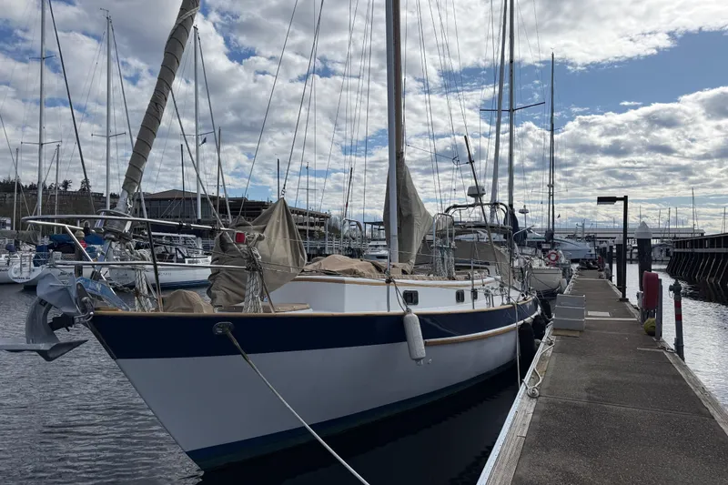 Slide: The Image of 1983 Valiant Cutter sailboat docked at marina under cloudy sky. - 17