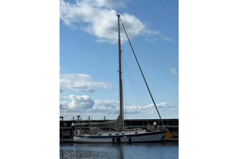 Slide: The Image of 1983 Valiant Cutter sailboat docked under a blue sky with clouds. - 18