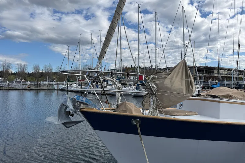 Slide: The Image of 1983 Valiant Cutter sailboat docked in a marina under a cloudy sky. - 19