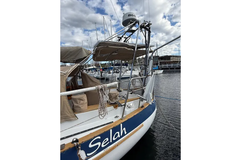 Slide: The Image of 1983 Valiant Cutter sailboat named "Selah" docked at marina under cloudy sky. - 22