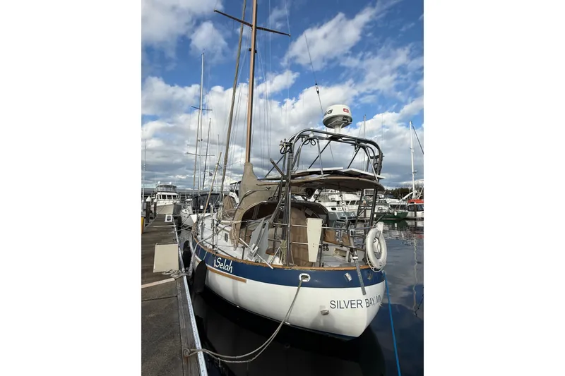 Slide: The Image of 1983 Valiant Cutter sailboat docked at marina under a partly cloudy sky. - 23
