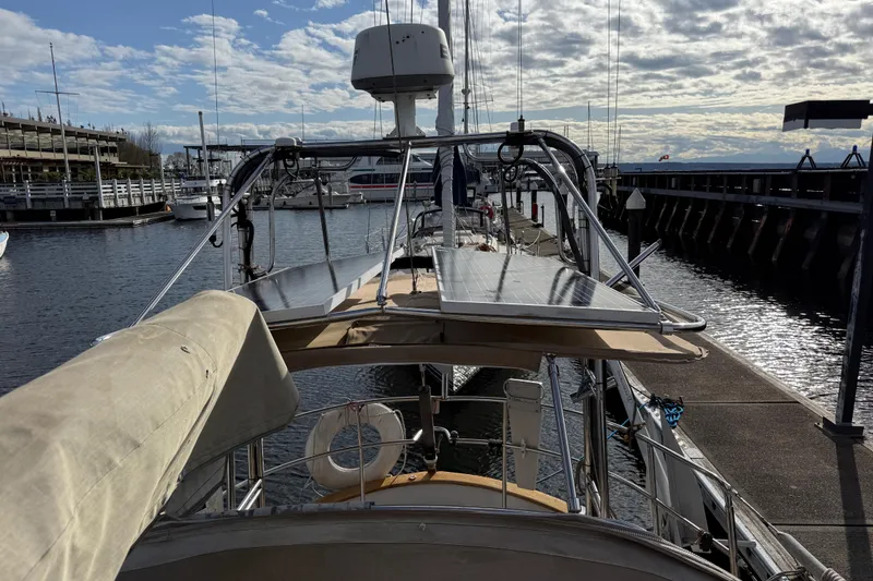 Slide: The Image of 1983 Valiant Cutter sailboat docked at marina under partly cloudy sky. - 26