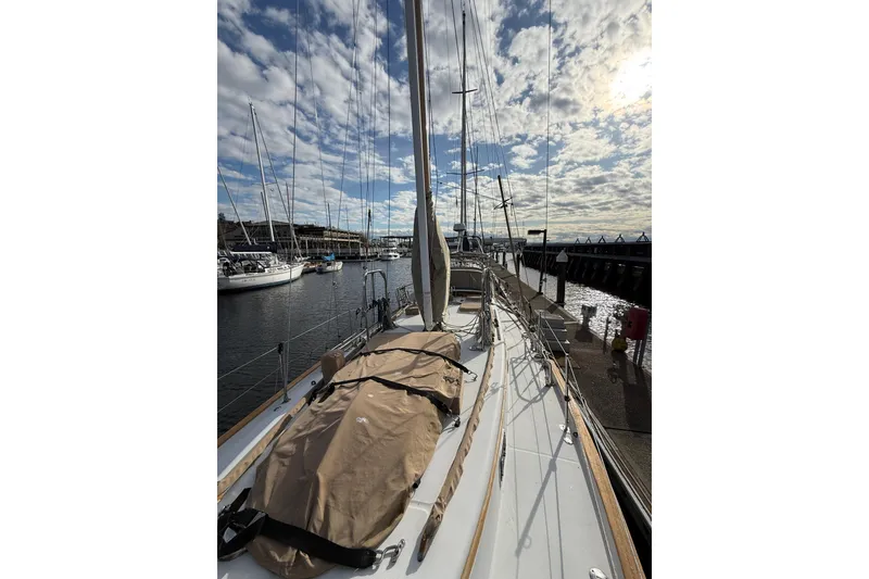 Slide: The Image of 1983 Valiant Cutter sailboat docked under a partly cloudy sky. - 27