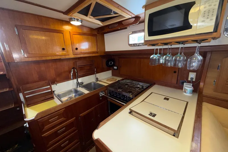 Slide: The Image of 1983 Valiant Cutter yacht kitchen with wooden cabinets, stove, and hanging wine glasses. - 4