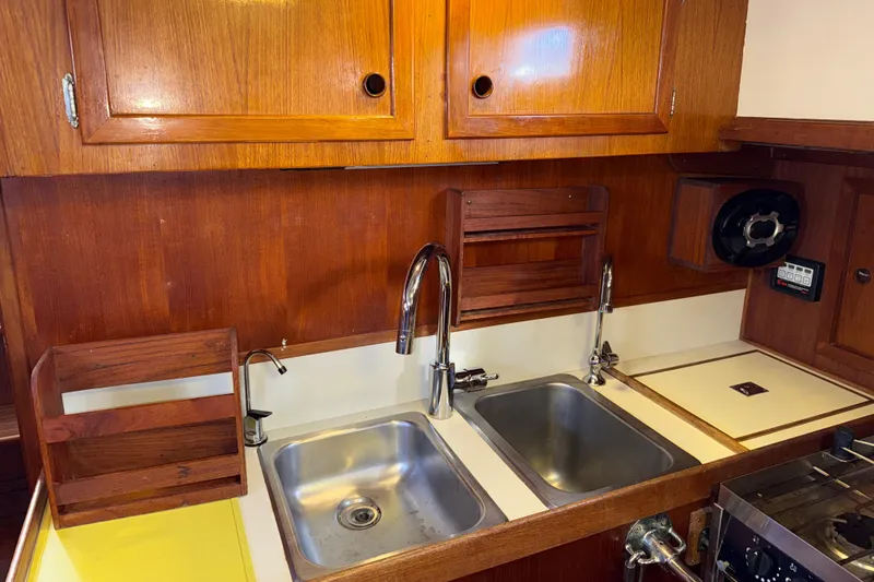 Slide: The Image of 1983 Valiant Cutter yacht kitchen with wooden cabinets and dual stainless steel sinks. - 5