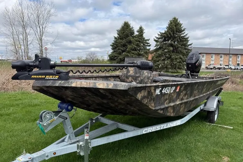 The Image of 2021 Crestliner 1760 Retriever SC boat on trailer, camo design, grassy area background. - 0