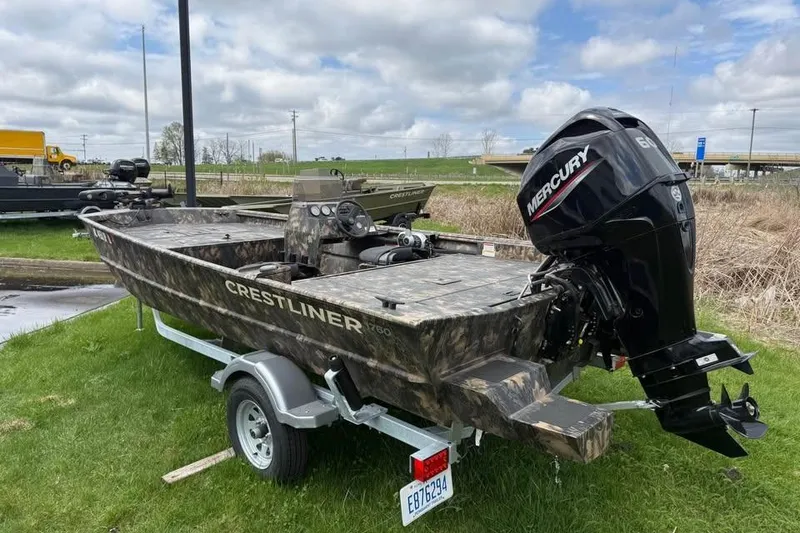 Slide: The Image of 2021 Crestliner 1760 Retriever SC boat with Mercury engine on trailer, parked on grass. - 2