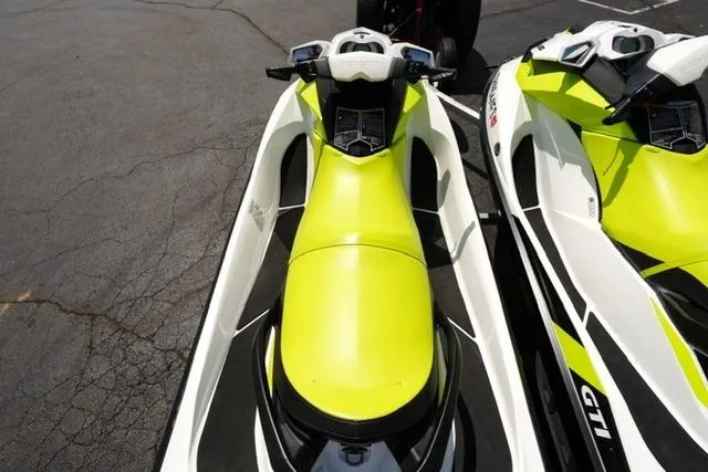 Slide: The Image of 2017 Sea-Doo GTI jet ski in vibrant yellow and white, parked on asphalt. - 7
