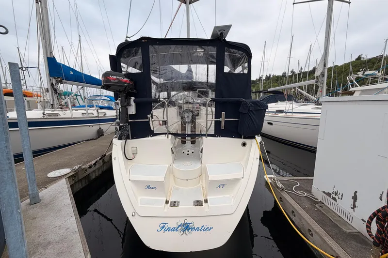 Slide: The Image of 1990 Hunter 37.5 sailboat docked, featuring a Mercury outboard motor and covered cockpit. - 17