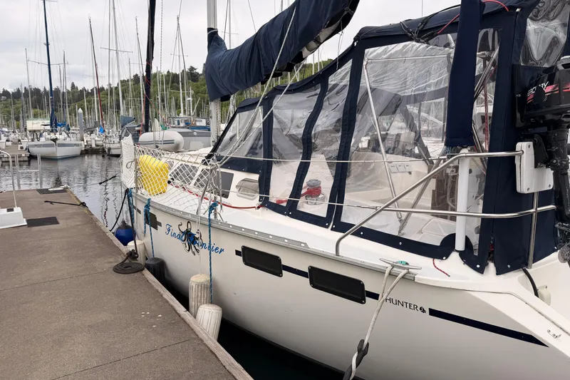 Slide: The Image of 1990 Hunter 37.5 sailboat docked at marina, featuring blue canvas covers and clear panels. - 19