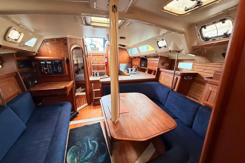 Slide: The Image of Interior of a 1990 Hunter 37.5 sailboat with wood finishes and blue seating. - 2