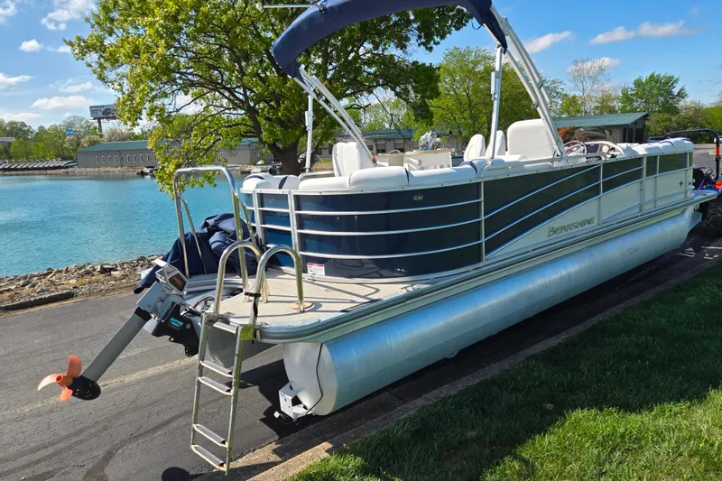 Slide: The Image of 2018 Berkshire 25E STS Entertainment pontoon boat by a lake, under a clear sky. - 1