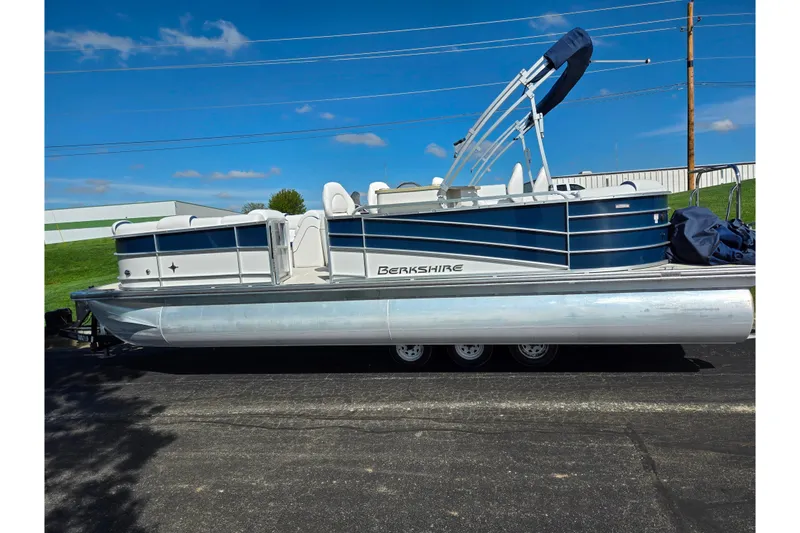 Slide: The Image of 2018 Berkshire 25E STS Entertainment pontoon boat on trailer, blue and white design. - 5