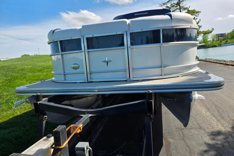 Slide: The Image of 2018 Berkshire 25E STS Entertainment pontoon boat on trailer by a lake. - 7