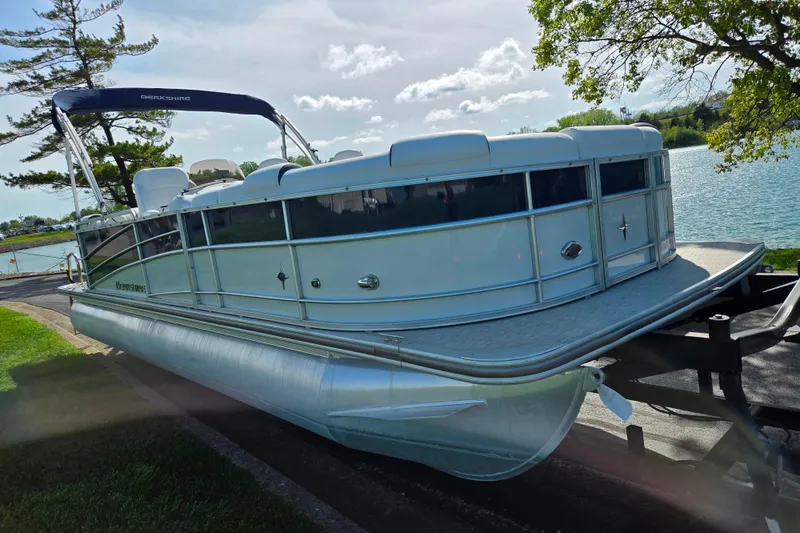 Slide: The Image of 2018 Berkshire 25E STS Entertainment pontoon boat on trailer by a lake. - 9