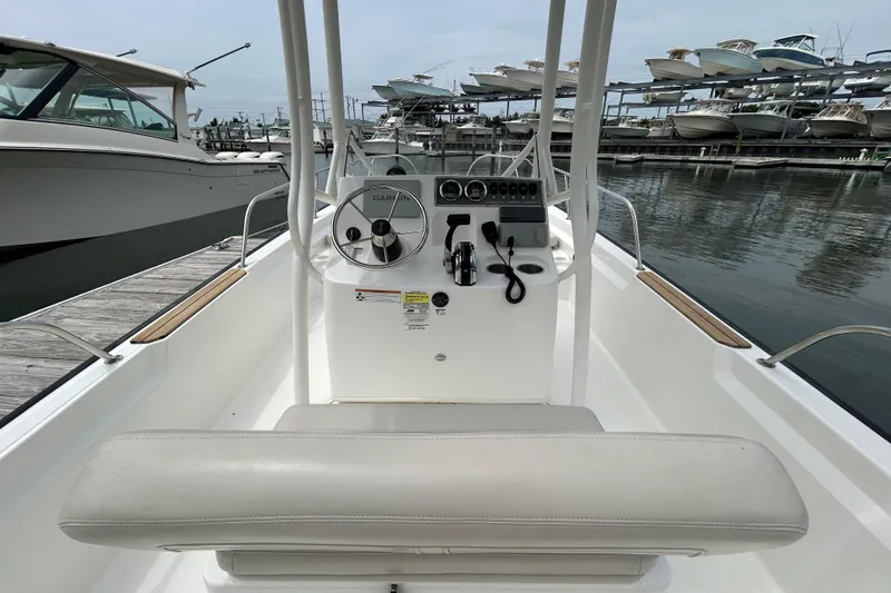Slide: The Image of 2022 Boston Whaler 190 Montauk boat console with steering wheel and controls at marina. - 12