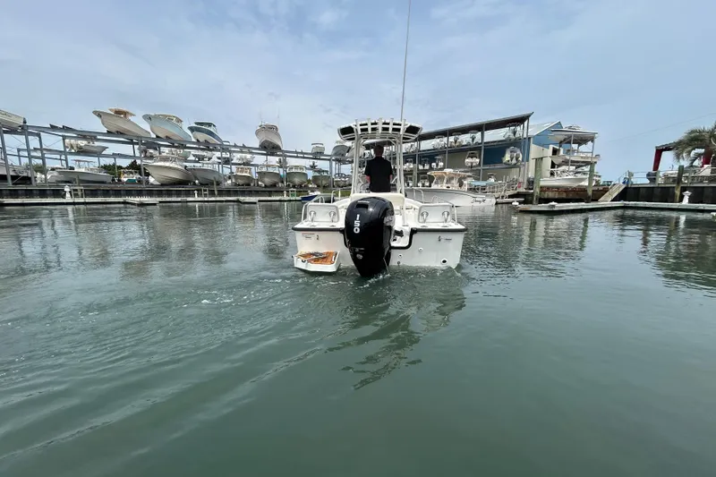 Slide: The Image of 2022 Boston Whaler 190 Montauk boat navigating marina waters, surrounded by docked vessels. - 5