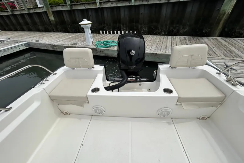 Slide: The Image of 2022 Boston Whaler 190 Montauk boat interior with seating and motor at dock. - 9