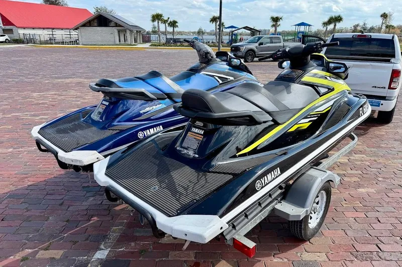 Slide: The Image of 2019 Yamaha WaveRunner VX Deluxe jet skis on a trailer in a parking lot. - 2