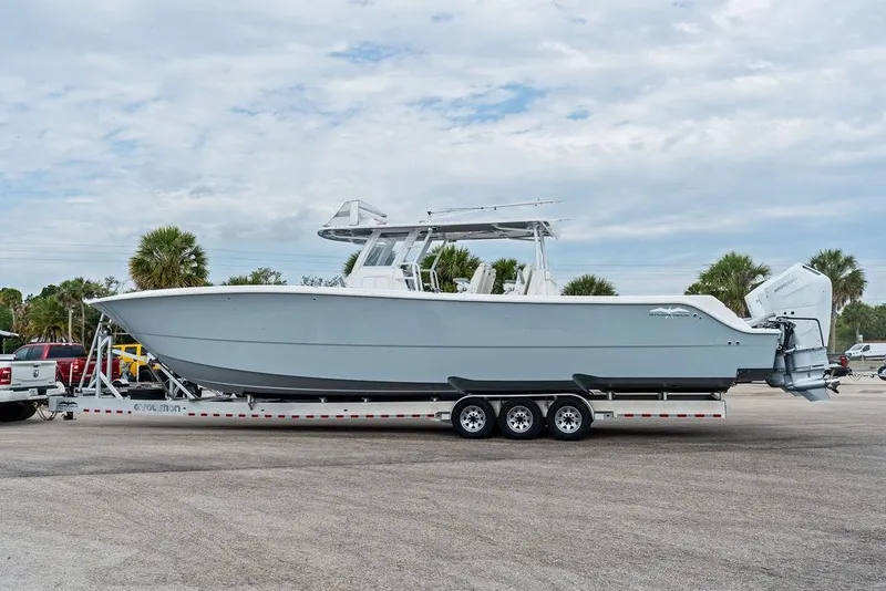 Slide: The Image of 2021 Invincible 46 Catamaran on trailer, parked outdoors with palm trees in background. - 55