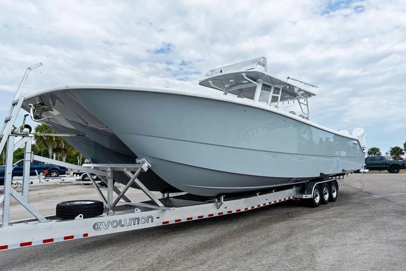 Slide: The Image of 2021 Invincible 46 Catamaran on trailer, parked outdoors under cloudy sky. - 56