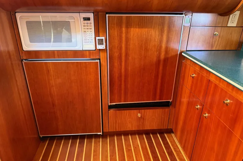 Slide: The Image of 2001 Tiara Yachts 5200 Express kitchen with wood cabinetry, microwave, and refrigerator. - 24