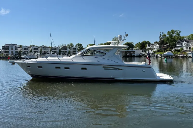Slide: The Image of 2001 Tiara Yachts 5200 Express cruising on a calm lake near waterfront homes. - 5