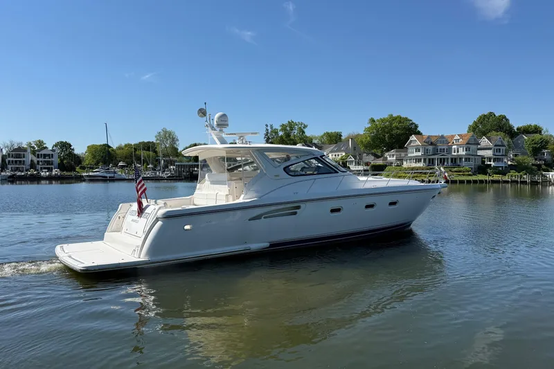 Slide: The Image of 2001 Tiara Yachts 5200 Express cruising on a serene lake near waterfront homes. - 7