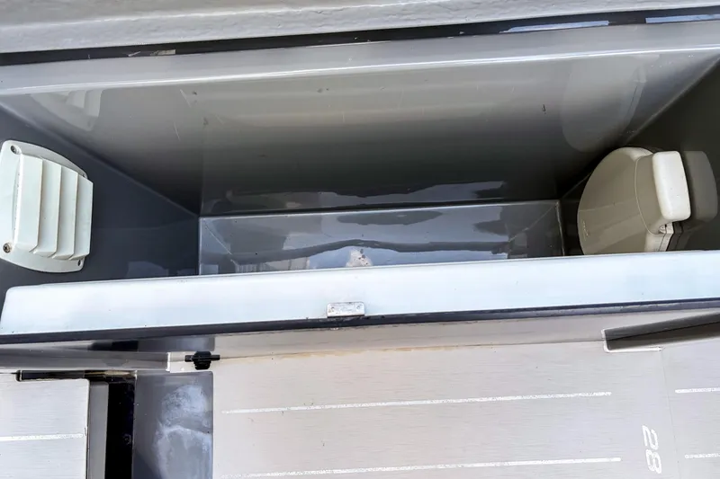Slide: The Image of 2017 Axopar 28 T-Top interior storage compartment with seating and ventilation. - 16