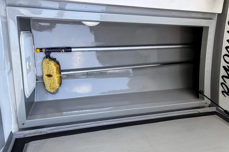 Slide: The Image of Storage compartment of 2017 Axopar 28 T-Top boat with cleaning brush inside. - 17
