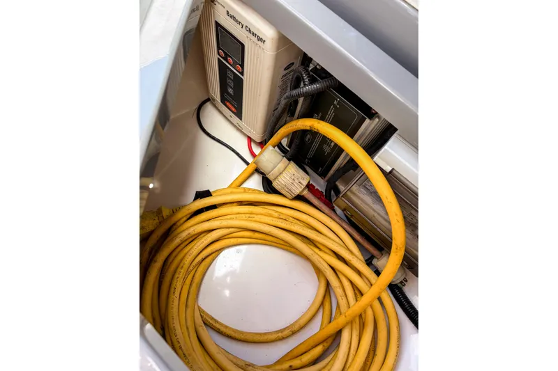Slide: The Image of Yellow power cable and battery charger inside 2017 Axopar 28 T-Top boat compartment. - 19