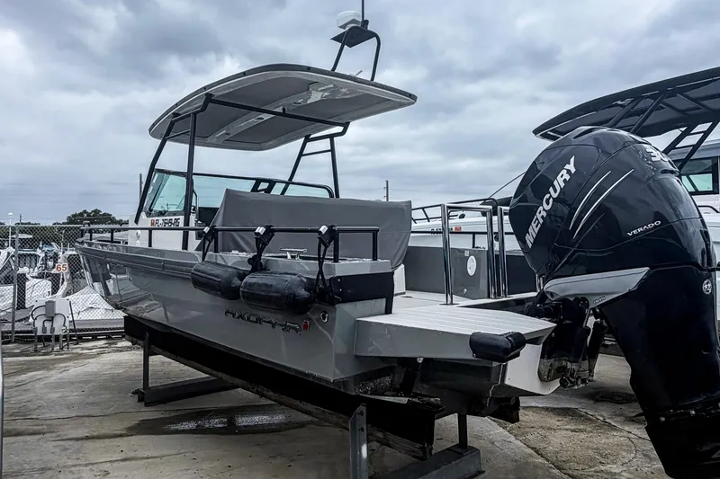 Slide: The Image of 2017 Axopar 28 T-Top boat with Mercury Verado engine, docked under cloudy skies. - 2