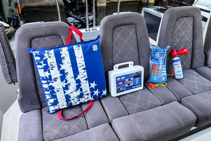 Slide: The Image of Safety equipment on 2017 Axopar 28 T-Top boat seats, including first aid kit and signal horn. - 25
