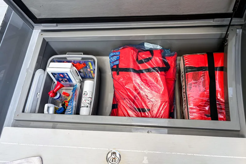 Slide: The Image of Storage compartment on a 2017 Axopar 28 T-Top with safety gear and life jackets. - 26