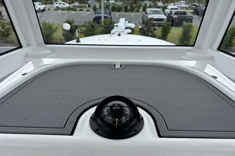 Slide: The Image of Compass on 2026 Caymas 26 HB boat dashboard, with parking lot view through windows. - 16