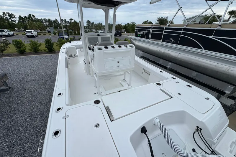 Slide: The Image of 2026 Caymas 26 HB boat interior with seating and storage, parked on gravel. - 7