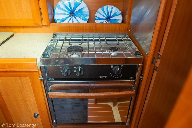 Slide: The Image of Compact kitchen stove in a 2008 Hunter 31 sailboat galley with wooden cabinetry. - 11