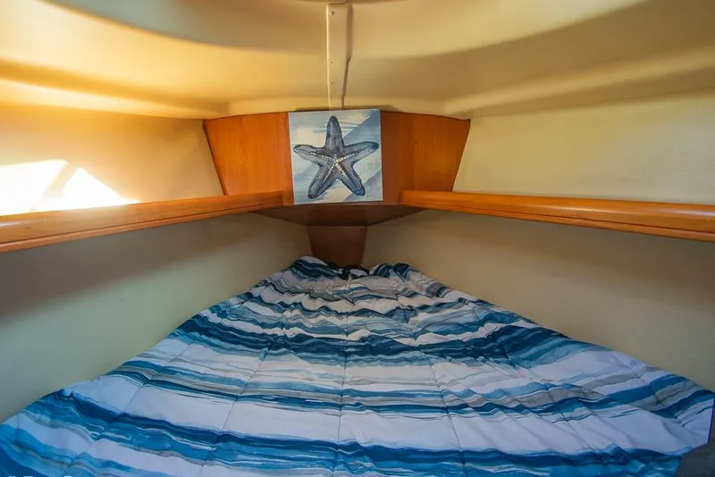 Slide: The Image of Cozy cabin interior of 2008 Hunter 31 sailboat with starfish decor and striped bedding. - 18