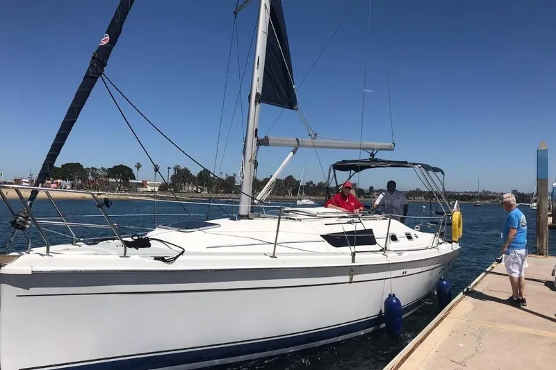 Slide: The Image of 2008 Hunter 31 sailboat docked with people onboard and nearby, under clear blue sky. - 38