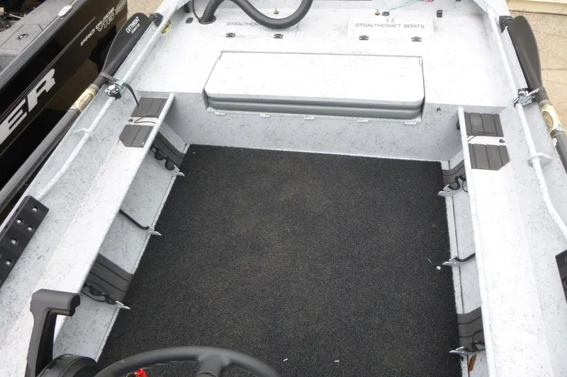 Slide: The Image of 2025 StealthCraft 16 StealthWeld boat interior with rod holders and carpeted floor. - 8