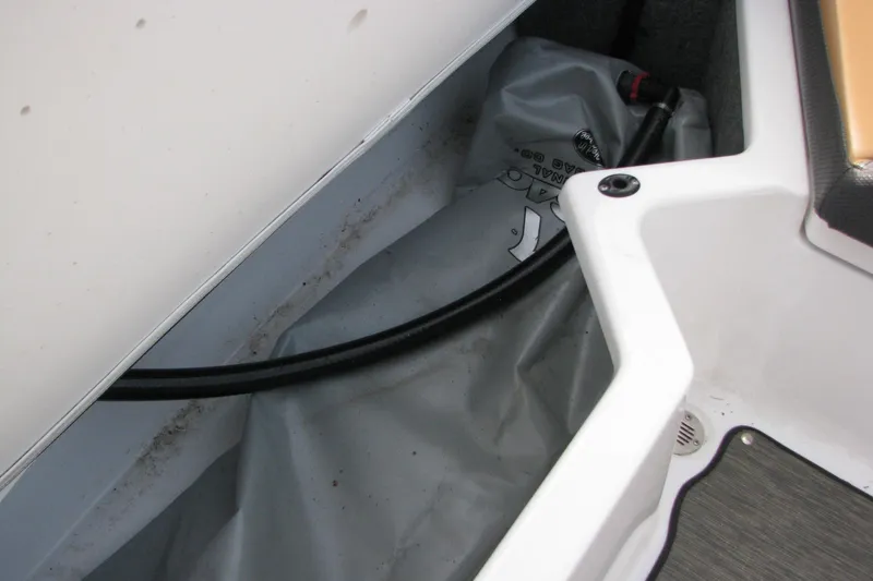 Slide: The Image of Storage compartment of a 2022 Scarab 215 ID boat, featuring a hose and cover. - 14