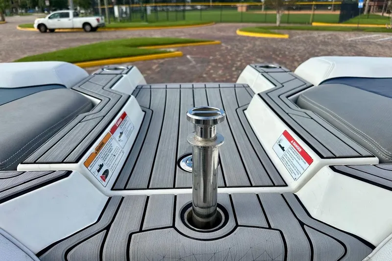 Slide: The Image of 2018 Nautique Super Air Nautique GS22 boat deck with seating and warning labels. - 22