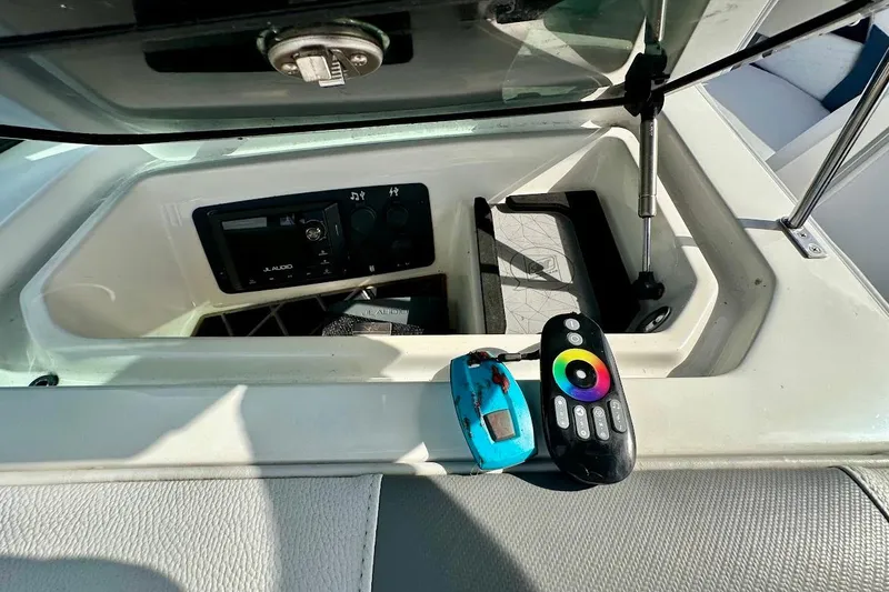 Slide: The Image of 2018 Nautique Super Air Nautique GS22 storage compartment with JL Audio system and remote controls. - 33