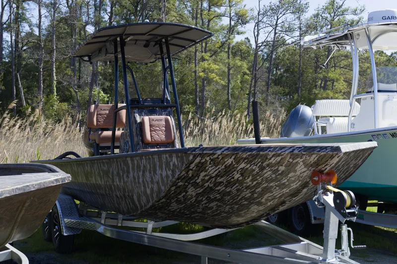 Slide: The Image of 2026 Avid 22 Recon boat with camouflage design on a trailer in a wooded area. - 3