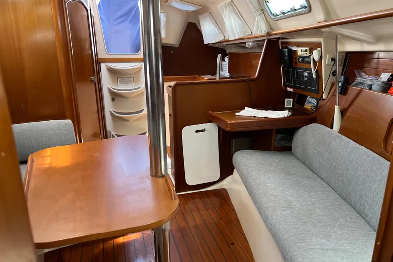 Slide: The Image of Interior of a 1999 Beneteau Oceanis 321 sailboat, featuring wood finishes and cozy seating. - 21