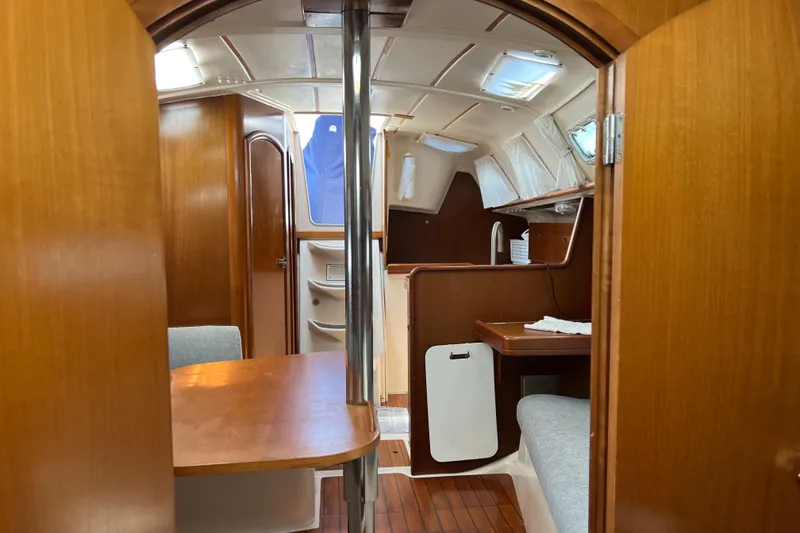 Slide: The Image of Interior of 1999 Beneteau Oceanis 321 sailboat, featuring wood finishes and cozy seating area. - 22