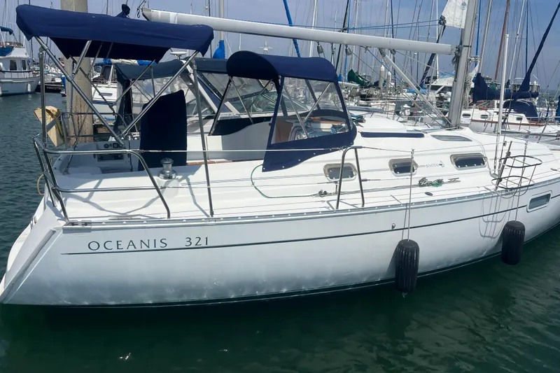 Slide: The Image of 1999 Beneteau Oceanis 321 sailboat docked in marina, featuring blue canopy and sleek design. - 37
