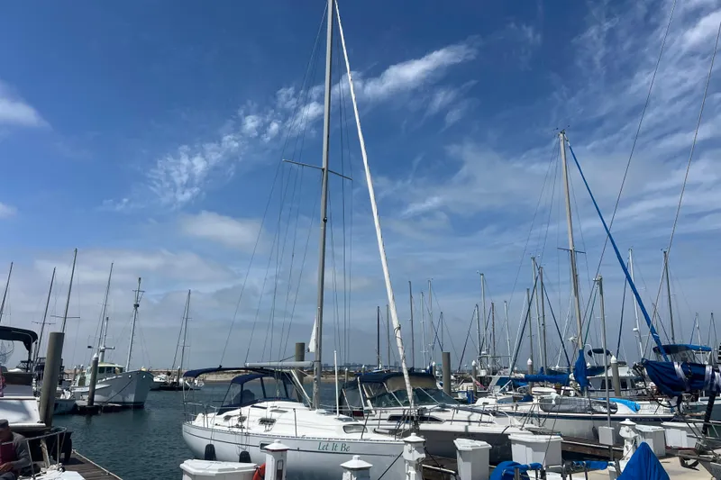 Slide: The Image of Sailboats docked at a marina under a clear blue sky, featuring a 1999 Beneteau Oceanis 321. - 39