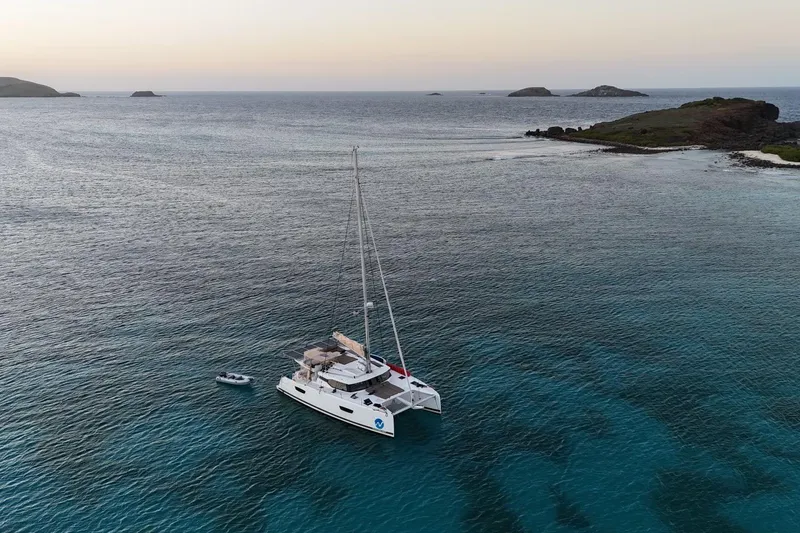 The Image of 2018 Fountaine Pajot Saona 47 catamaran anchored in serene coastal waters at sunset. - 0