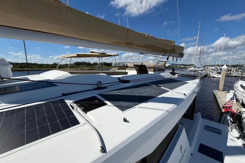 Slide: The Image of 2018 Fountaine Pajot Saona 47 catamaran with solar panels, docked at a marina under blue skies. - 12